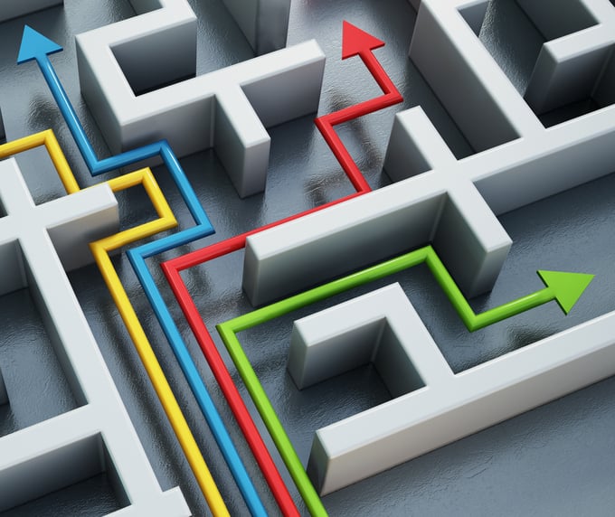 Four colored arrows—blue, yellow, red, and green—navigate different paths through a white 3D maze.